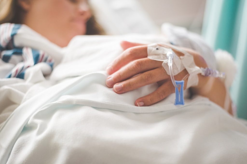 a-woman-laying-in-a-hospital-bed-with-an-iv-in-her-hand-gwgfpdxisis